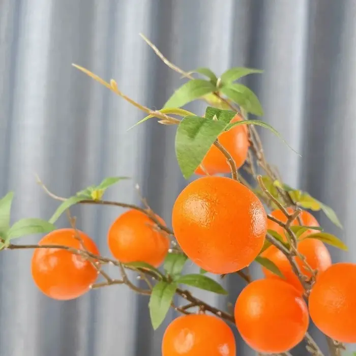 Branche d'orange artificielle avec feuilles vertes réalistes