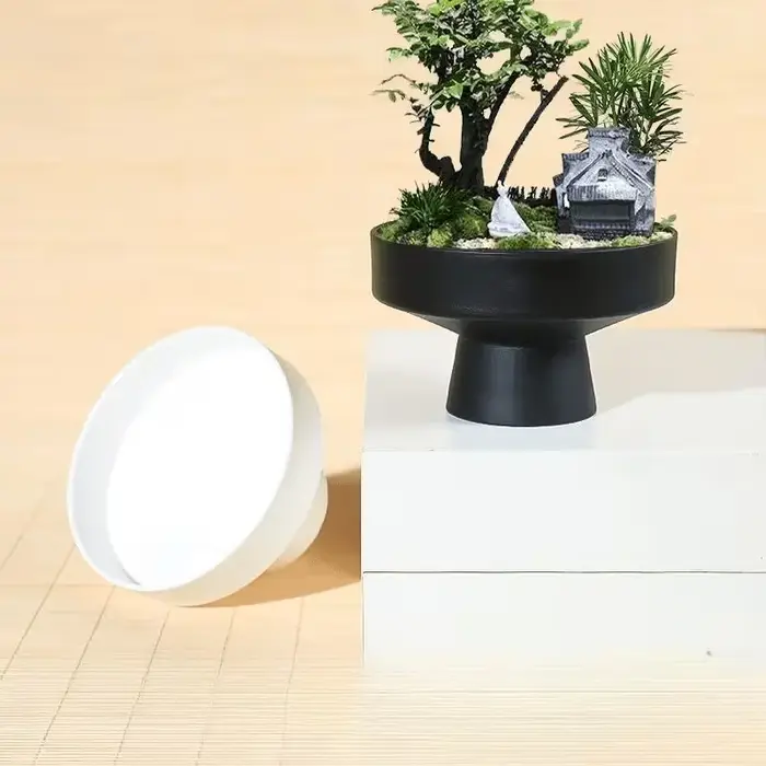 Pot de fleurs noir minimaliste moderne avec base large et peu profonde et pieds hauts pour la décoration du jardin domestique