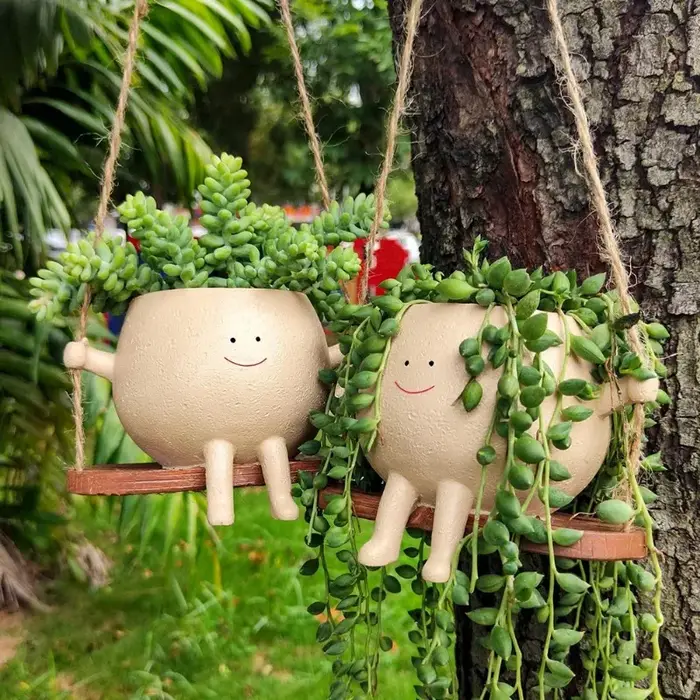 Pot de fleurs créatif en forme de tête de personne assise sur une balançoire