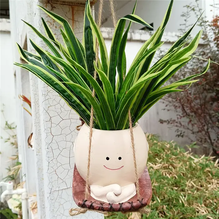 Pot de fleurs créatif en forme de tête de personne assise sur une balançoire