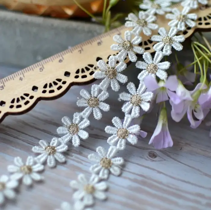 Tissu en dentelle brodée de fleurs de marguerite dorées