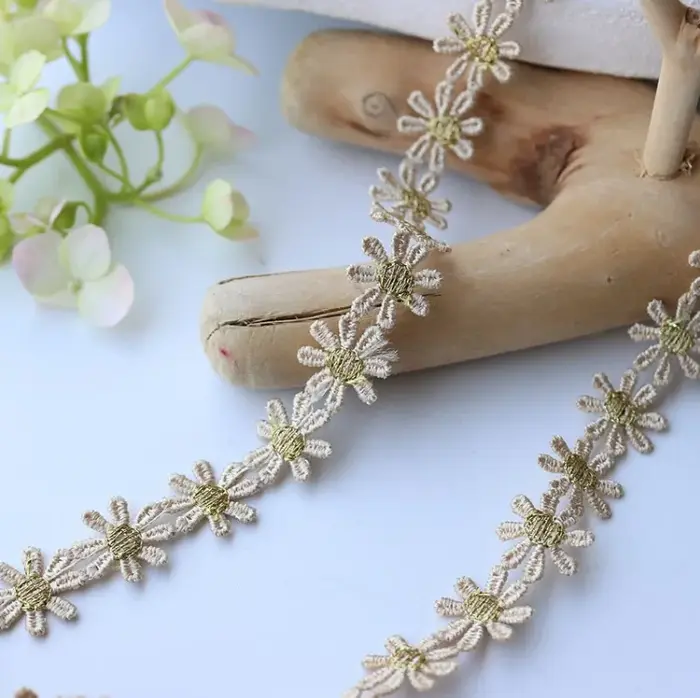 Tissu en dentelle brodée de fleurs de marguerite dorées